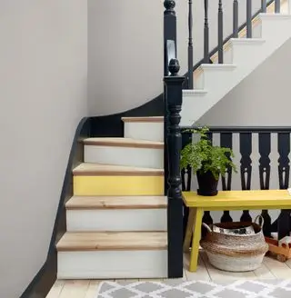 Escalera con balaustradas negras, newel y pasamanos y contrahuellas blancas y amarillas