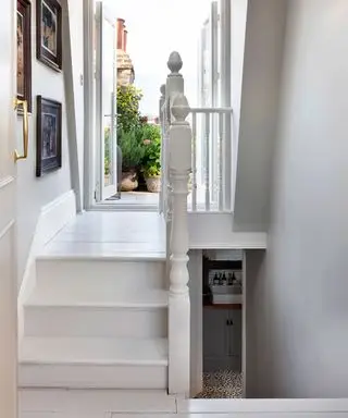 zona de aterrizaje pintada de blanco, escaleras de madera pintadas, puertas abiertas que conducen a una terraza en la azotea