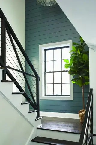 Escalera de madera con contrahuellas pintadas y balaustrada negra.