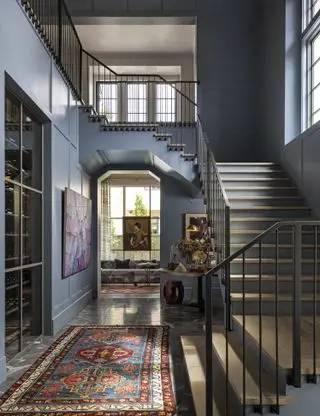 Pasillo con alfombra en el piso y escalera y vista al salón con pintura azul en las paredes