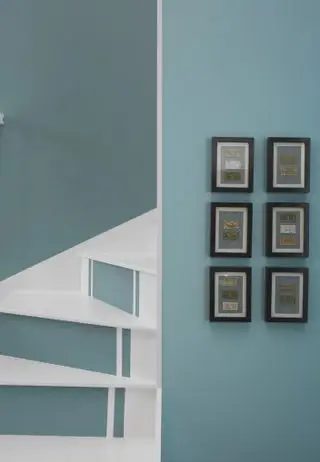 Escalera con contrahuellas pintadas de azul con peldaños blancos y blancos y pared azul