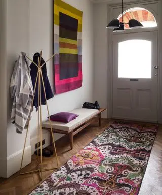 Nápady do úzké haly s růžovým a fialovým vzorovaným běhounem a uměleckými díly.
