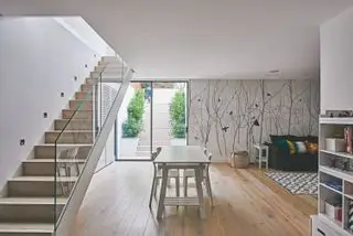 Kjeller med trapp og klar baluster, tregulv, spisebord og funksjonsvegg