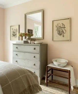 dormitorio shabby chic con paredes de color rosa pálido, tocador gris y espejo