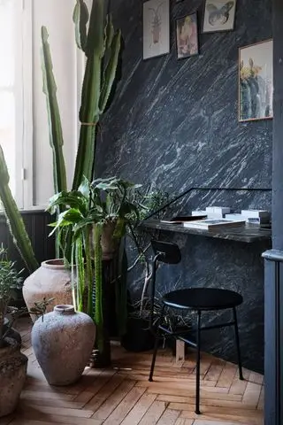 soveværelse hjemmekontor med marmorvæg og skrivebord, sort stol, potter og planter, kaktus, kunst på væggen, sildebensgulv