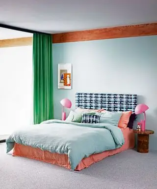 Modernes Schlafzimmer mit einem Doppelbett mit grüner Bettwäsche, rosa Nachttischlampen und grünen Vorhängen.