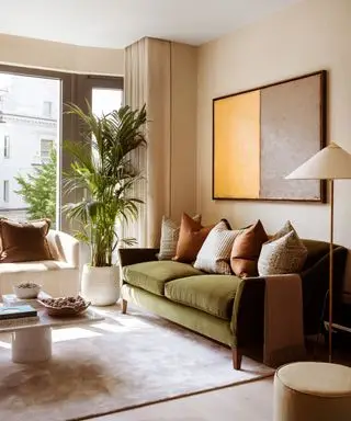 Uma sala neutra com grandes janelas e um sofá de veludo verde