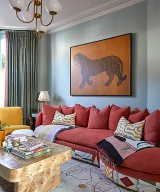 Uma sala de estar maximalista com obras de arte e um sofá curvo vermelho