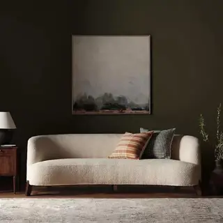 Biała sofa z poduszkami na tle ciemnozielonej ściany.
