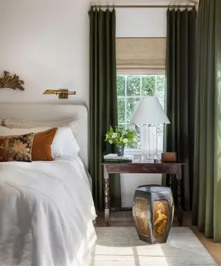 Dormitorio pequeño con cortinas verdes colgadas hasta el techo.