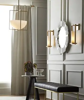 Uma ideia de iluminação de corredor combinando pingente de teto dourado contemporâneo e arandelas da Arteriors