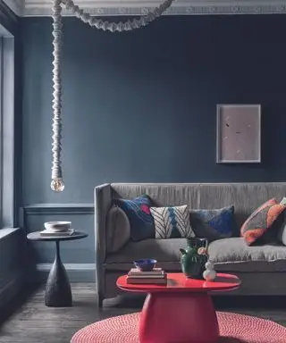 sala cinza escuro com sofá azul marinho e mesa de centro vermelha