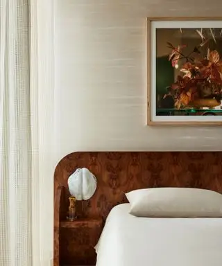 Una camera da letto neutra con una grande testiera in legno e sopra una grande opera d'arte