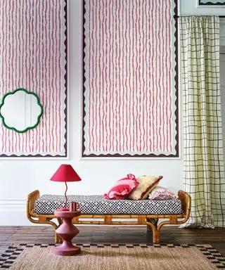Lille daybed med træramme, polstret sæde, to store kunstværker på væggen bagved, grønt scalloped spejl, mørkt trægulv, buet sidebord og matchende bordlampe