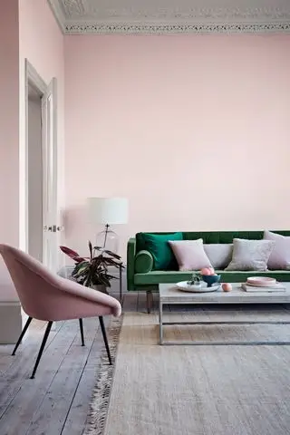 sala rosa com sofá verde, grades no chão, mesa de centro, abajur, poltrona rosa, almofadas rosa