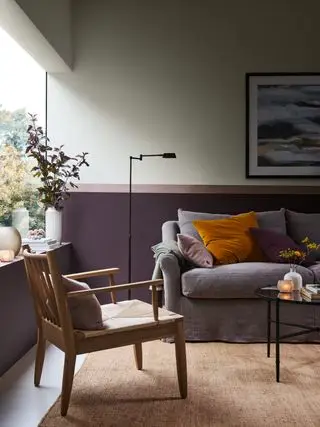 salon avec peinture aubergine violette sur rail dado, canapé gris, œuvres d'art, sol blanc, tapis texturé