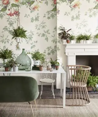 Idéias para lareira de primavera com plantas verdes em vasos brancos sobre uma lareira branca com papel de parede verde e branco inspirado na natureza