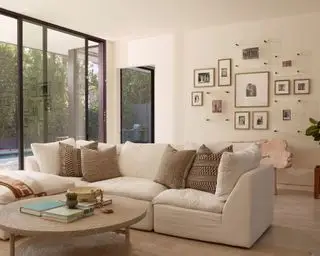 Stor, lys stue, minimalistisk stil med creme sofa, fotogallerivæg, rundt sofabord