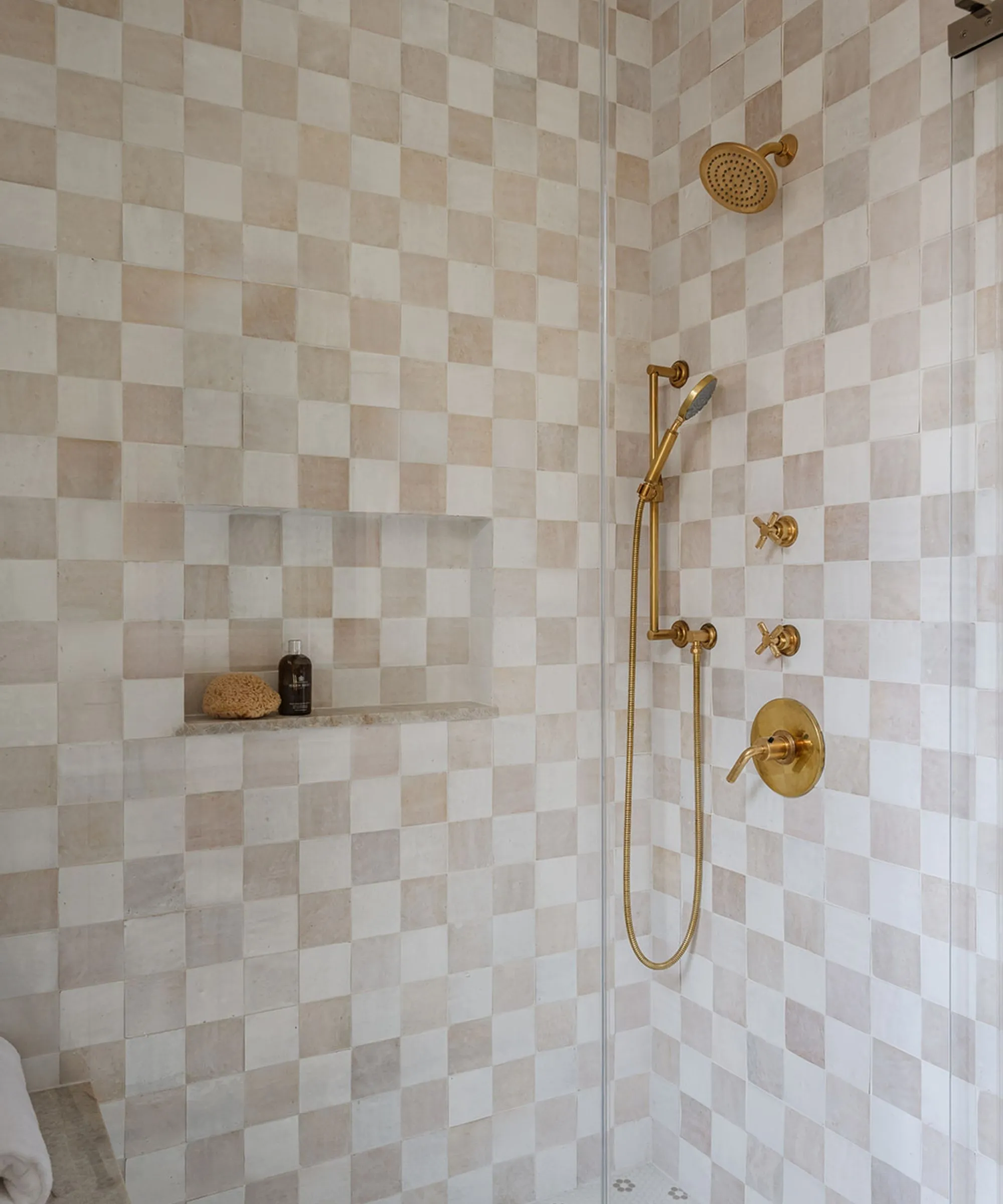 Walk in shower med guld hardware og skakternet creme og lyserøde fliser' loading='lazy' title=