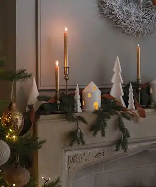 Nærbilde av dekorert mantel med julepynt og løvverk