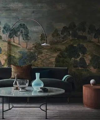 Un salón alegre con un gran mural azul y verde, un sofá y una lámpara de pie.
