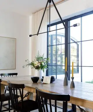 Uma sala de jantar branca com mesa de madeira e detalhes em preto