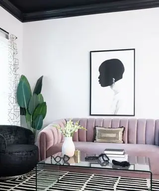 Uma sala branca com sofá de veludo rosa