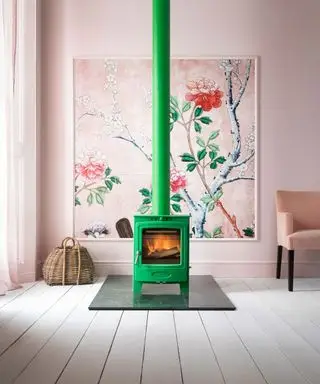 ピンクのリビング ルームに明るい緑のストーブ、花柄のフレームの壁紙、白い塗装の木製床板、