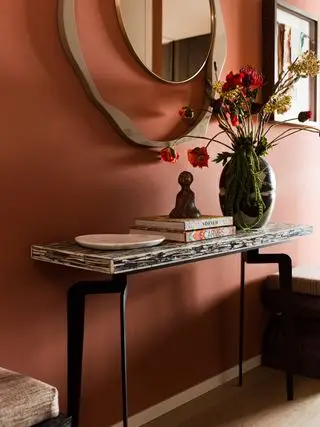 ingresso in terracotta con specchio scultoreo, consolle, pavimento in legno, fiori