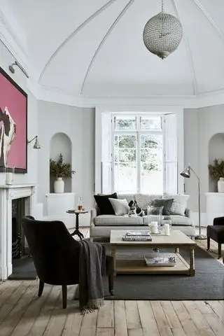 soggiorno bianco e grigio con soffitto a volta, alcove, divano grigio, pavimenti in legno, opere d'arte, lampadario, bovindo