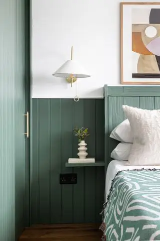 dormitorio verde con machihembrado pintado, paredes blancas, aplique blanco, obras de arte, estante pequeño, pisos de madera, manta abstracta verde