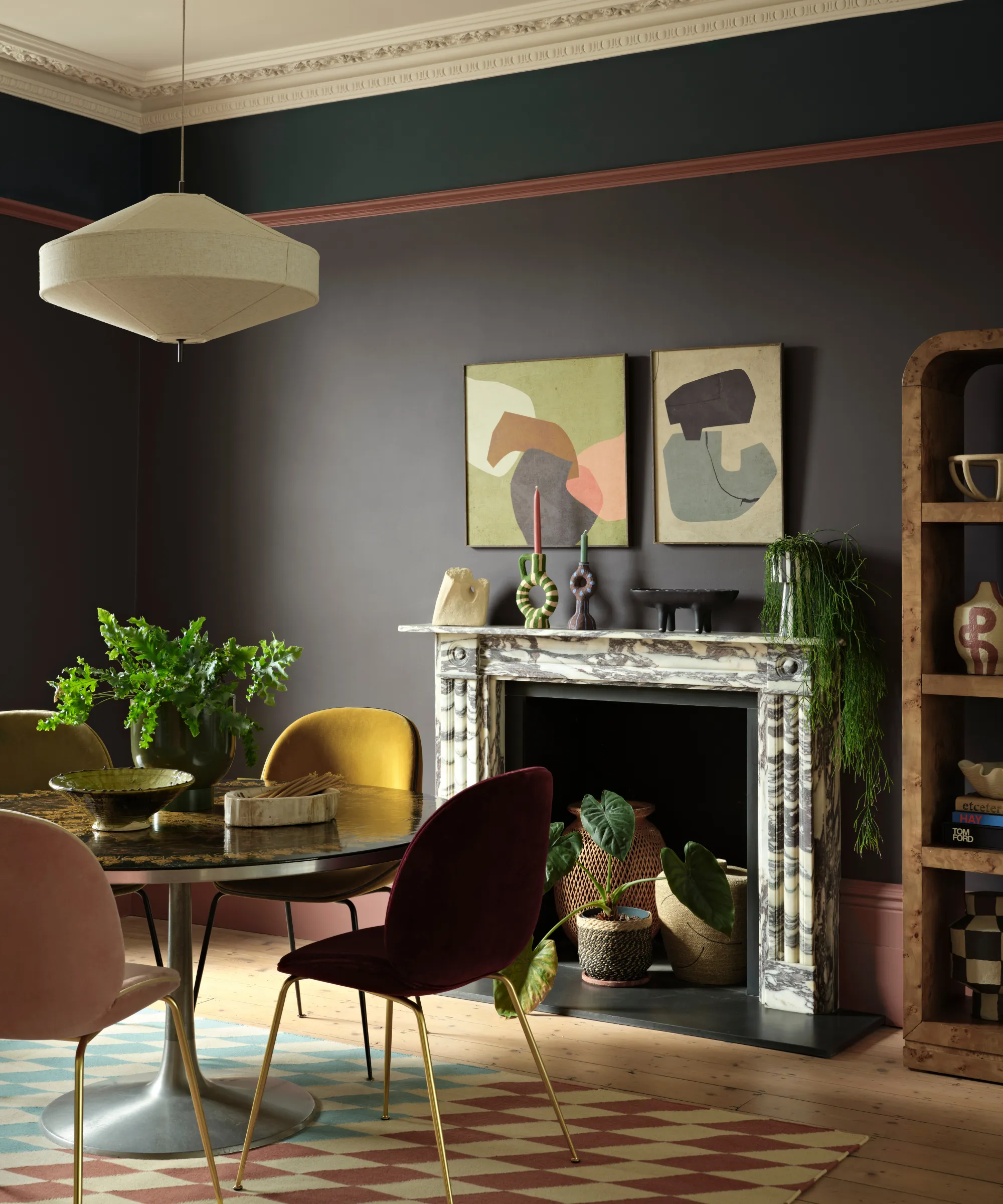 une salle à manger avec une petite table ronde avec quatre chaises colorées une cheminée en marbre avec des objets décoratifs sur le manteau une suspension en tissu suspendue au-dessus de la table et des murs peints avec la Silhouette de Benjamin Moore' loading='lazy' title=