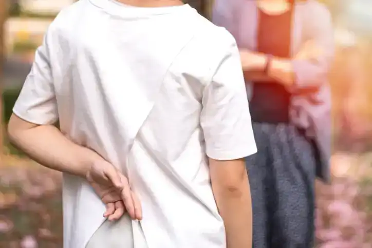 Liar female child hand crossing fingers behind back with father in front. lie and cheating, problem child. April Fools