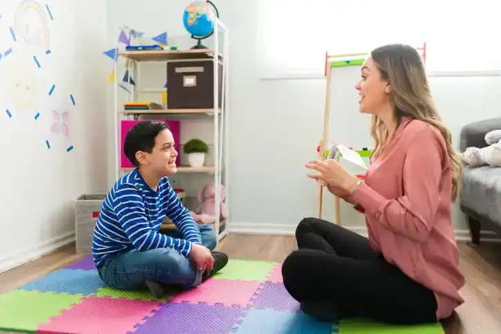 10 year old boy sits with speech therapist to fix hypermedia
