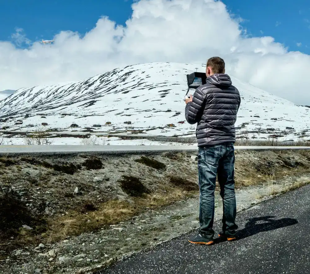 man with drone near mountain
