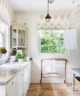 petite buanderie, avec un étendoir à poulie, une tringle à vêtements en bois et un comptoir en pierre dans un décor neutre et blanc.