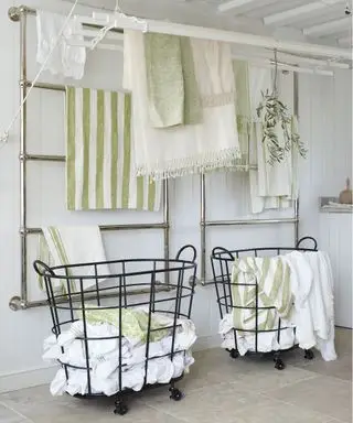 Comment organiser une buanderie avec des étendoirs muraux, dans un décor blanc avec des accents vert pâle.