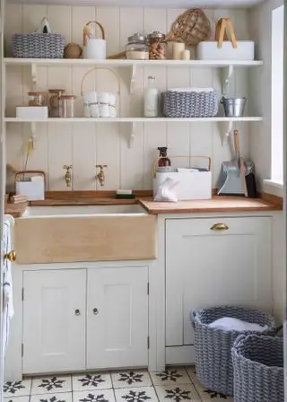 Une petite buanderie avec des étagères ouvertes peu encombrantes dans un décor blanc avec des carreaux de sol à motifs.