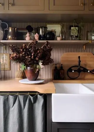 Idées de petites buanderies dans un décor en bois peint en marron avec un pichet de fleurs séchées à côté d'un évier de majordome.