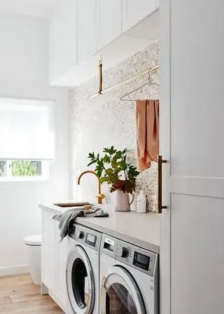 Idées de petites buanderies incorporées dans une salle de bain blanche avec des carreaux de mosaïque et un robinet doré.