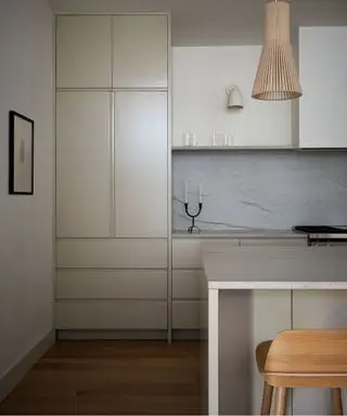 cozinha neutra com luminária pendente de vime e banco de ilha de cozinha de madeira