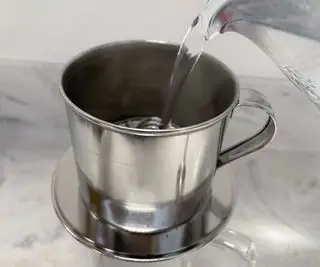Verser de l'eau dans une cafetière vietnamienne phin