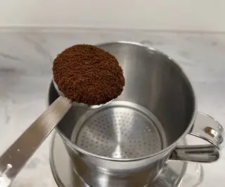 Cafetière vietnamienne phin avec une boule de café moulu