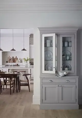 Cómoda despensa gris con puertas acristaladas y cocina blanca detrás
