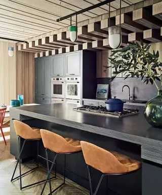 Holzküche mit Paneeldecke, schwarzer Insel und Anhängern