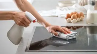 מישהו מנקה כיריים מזכוכית עם ספוג וסבון