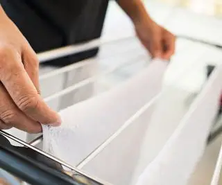 Un uomo che stende i vestiti su un stendibiancheria bianco riscaldato
