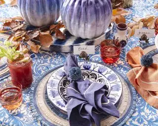 Ideas para centros de mesa de Acción de Gracias con mantel estampado azul y blanco, hojas de otoño y decoraciones de calabazas azules