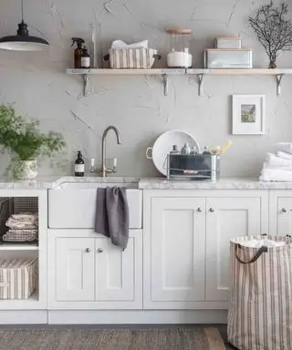 Buanderie moderne de ferme avec un panier, beaucoup de linge de maison, des armoires blanches et des murs neutres