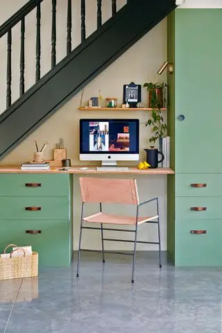 ホームオフィスは、机とラップトップを備えた階段の下の緑のキャビネットに組み込まれています